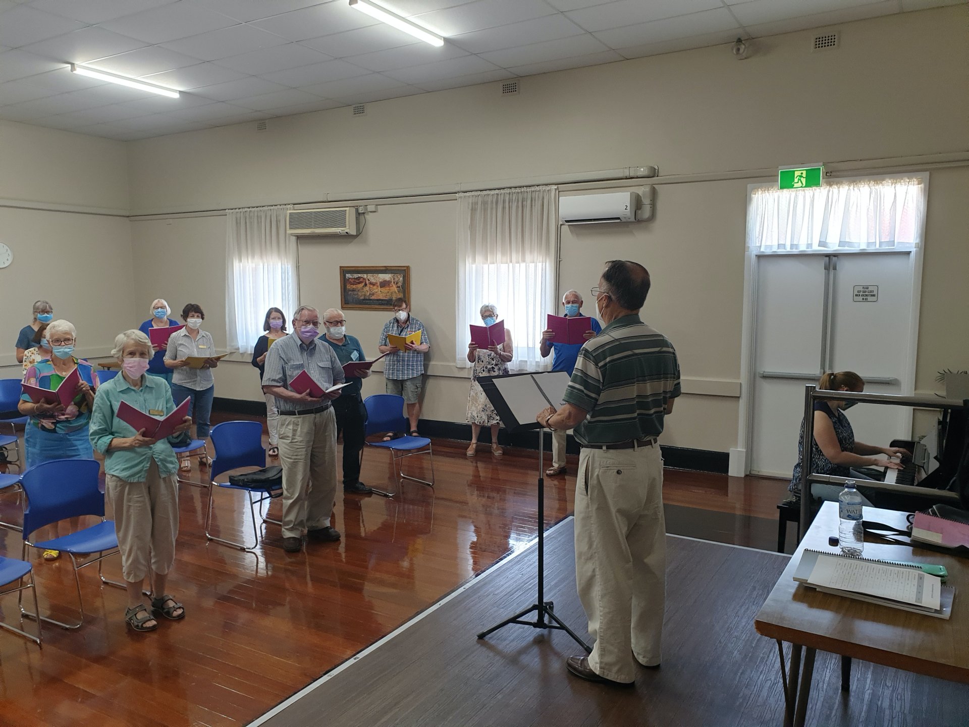 A group of elderly people participating in a choir whilst wearing protective face masks