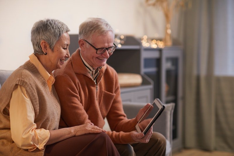 A man is reading an article on his tablet to his wife with dementia